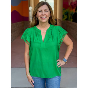 Woman wearing a green blouse with lace sleeves in an outdoor setting