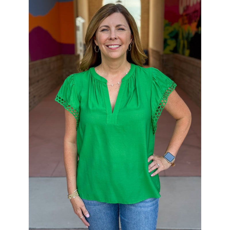 Woman wearing a green blouse with lace sleeves in an outdoor setting