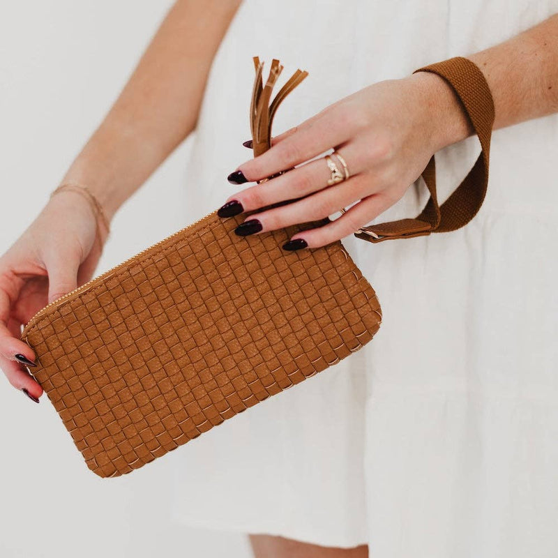 Brown woven clutch held by a person with a plain background