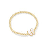 Gold beaded bracelet with a white butterfly charm on a white background
