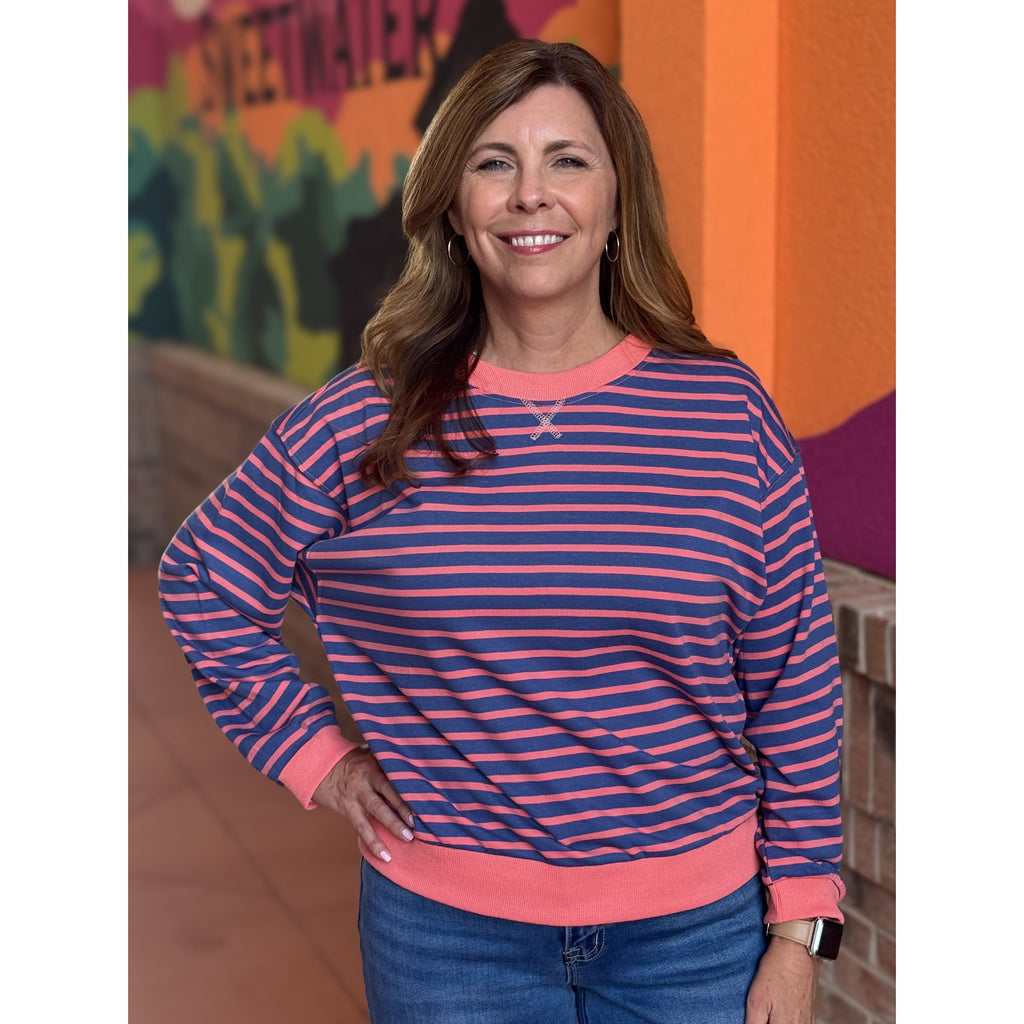 Woman wearing a blue and pink striped sweater with a colorful background