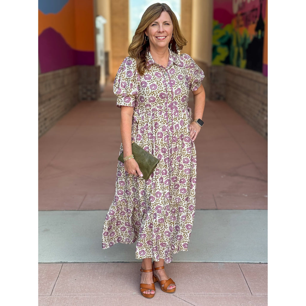 Woman in a floral dress standing in front of a colorful mural.