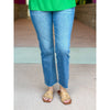 Person wearing blue jeans and a green top on a neutral background